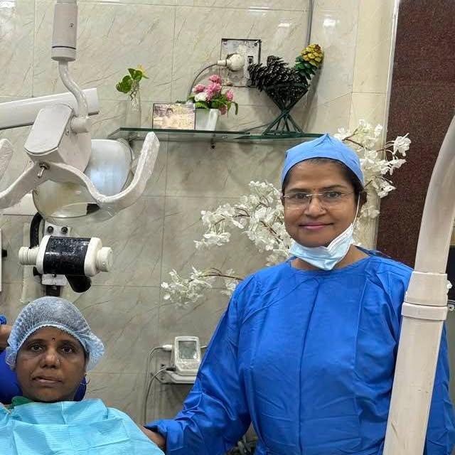 Dr. Alka Khade in surgical attire performing a dental procedure